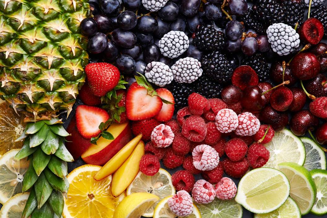 A collage of fresh fruit ice cream toppings, pineapple, strawberries, raspberries, blackberries cherries, oranges, peaches and pineapples.